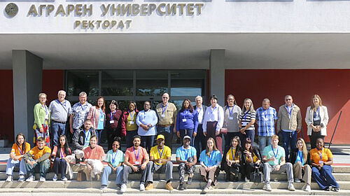 Gruppenfoto von Menschen vor einem Gebäude mit der Aufschrift 'Аграрен Университет Ректорат'